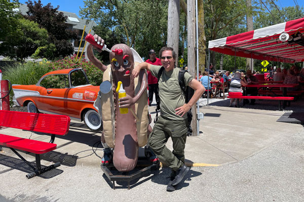 guys standing next to hotdog stand posing for photo
