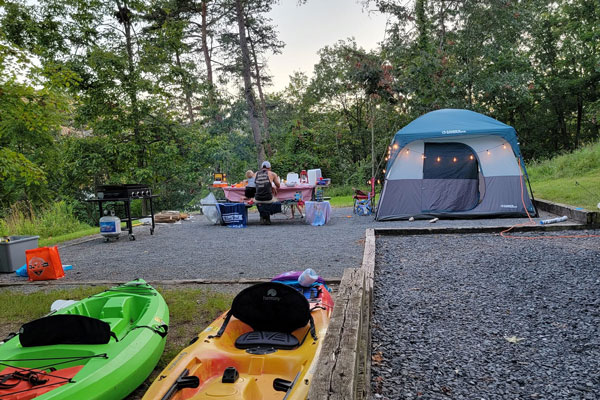 people sitting on bench kayaks docked  and tent a side