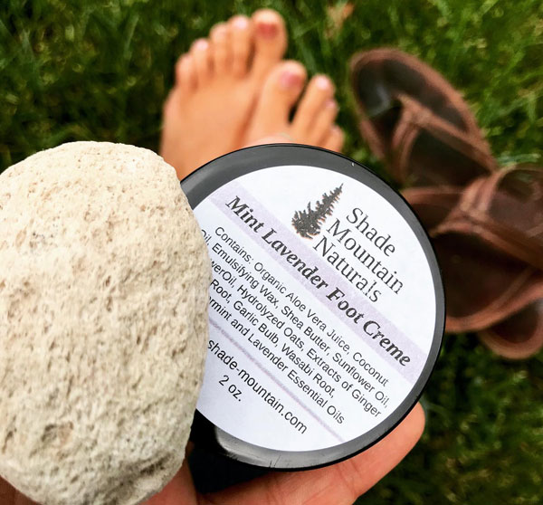 holding foot cream box and a pumice stone with foot and flips behind