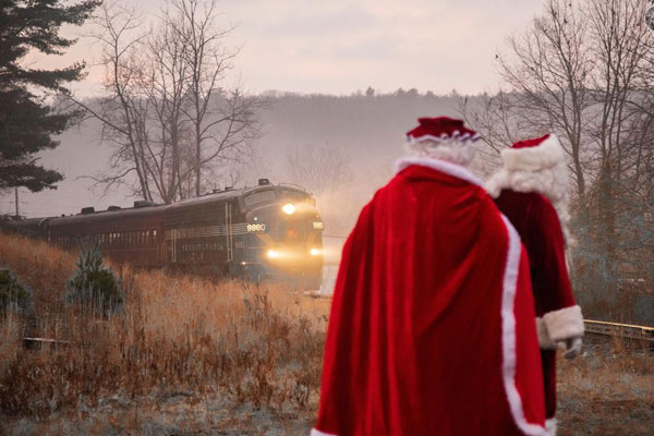 A person in a red coat and hat standing in front of a train