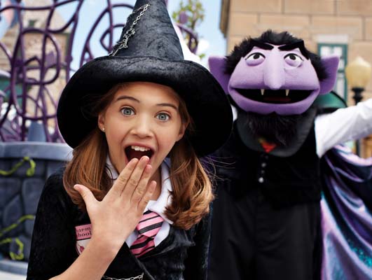 A person with a mask on the face next to a Girl with Halloween Costume