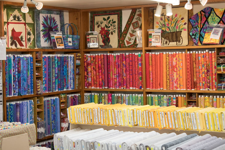 A room with shelves of Quilt bundles