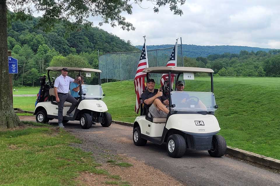 Guys in two golf carts driving down the course