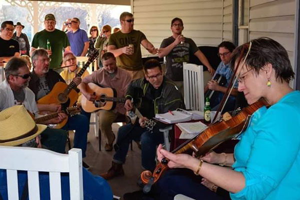 group of people playing guitars and a Violin while others enjoying music and drinking beer