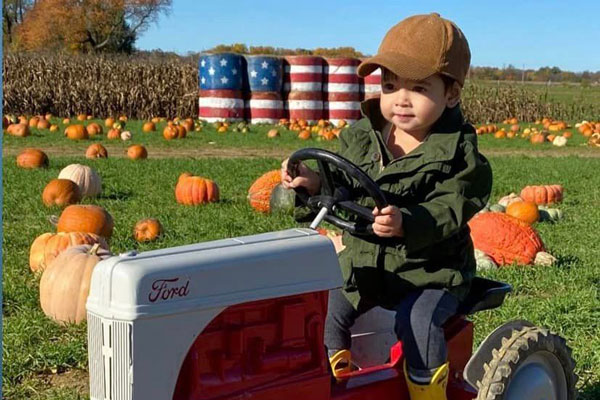 kids running a toy tractor on pumpkin patch