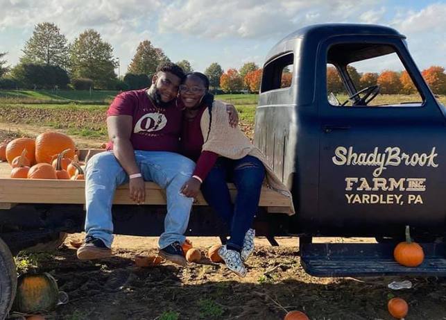 couple sitting on a pumpkin wagon