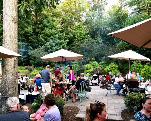 A photo of an outdoor patio filled with people enjoying wine under umbrellas at Seven Mountain Wine Cellars in Pennsylvania