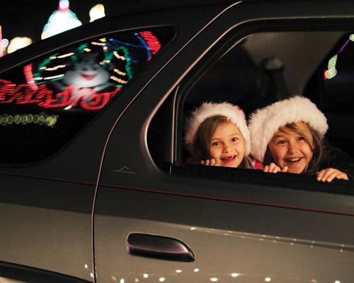 kids watching holiday lights from car