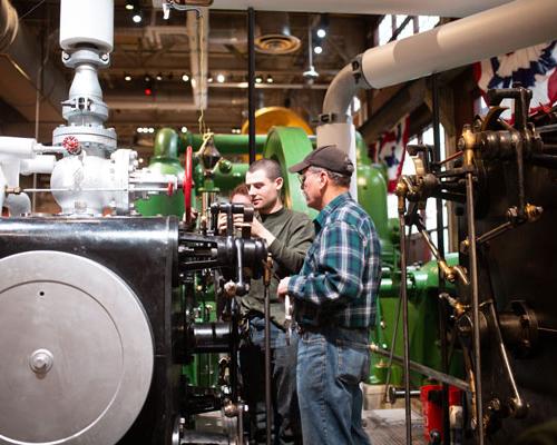 two guys checking heavy machinery Inside national Museum of Industrial History