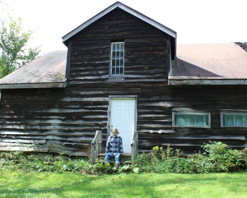 A scarecrow sitting outside a log cabin