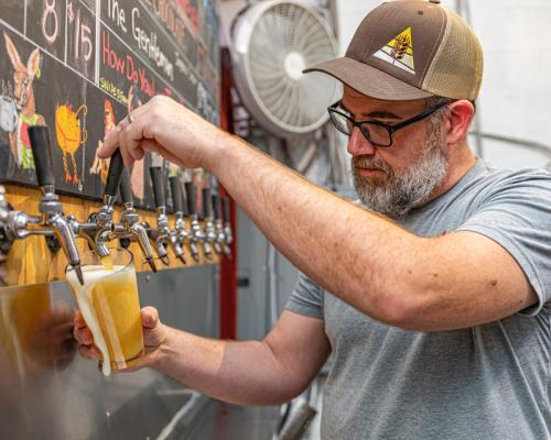a person pouring beer into glass from tap