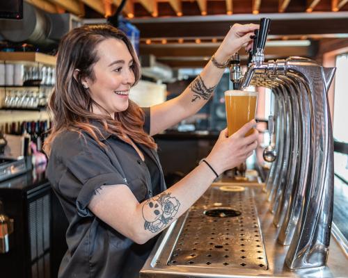 bartender pouring beer into glass from tap