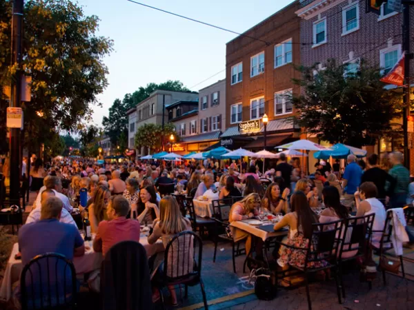 People dining at outdoor tables on a Main Street in a downtown at dusk