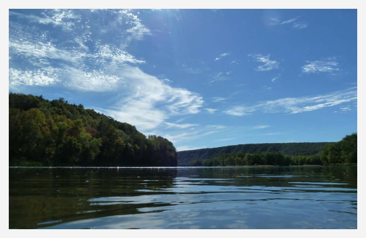 A calm lake with hills an trees in the distance