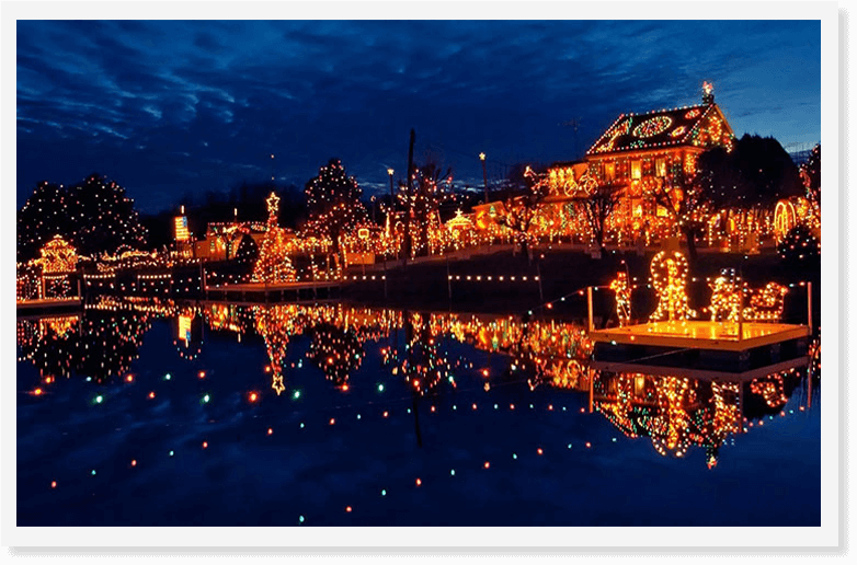 Christmas village by pond with lights and decorations at night