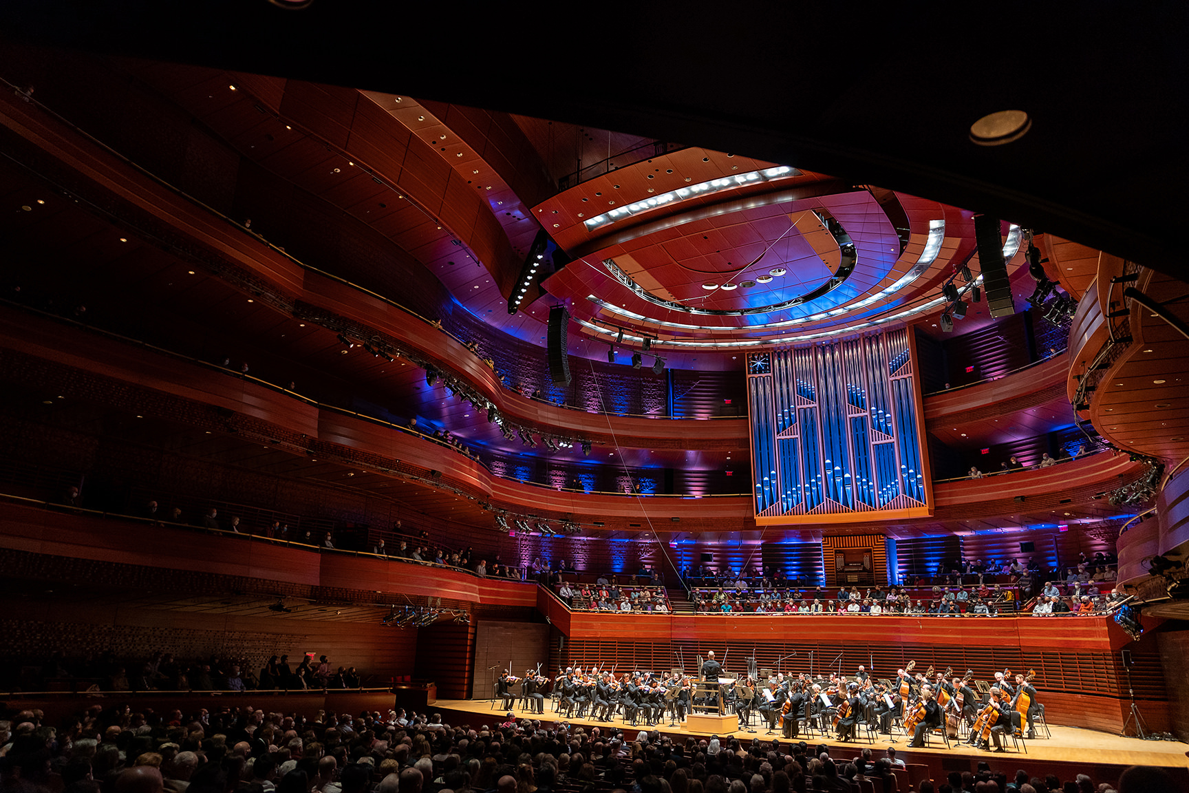 Theater interior, an orchestra plays in from of a crowd.