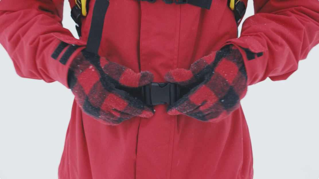 A person in a red jacket buckling a harness